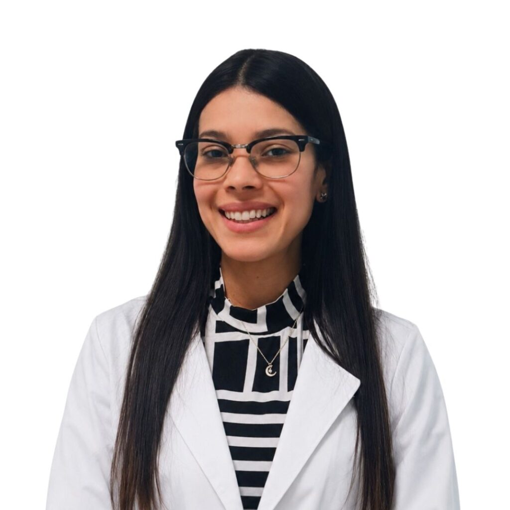 Smiling woman with long dark hair and glasses, wearing a white lab coat over a black-and-white striped blouse, posed against a white background.