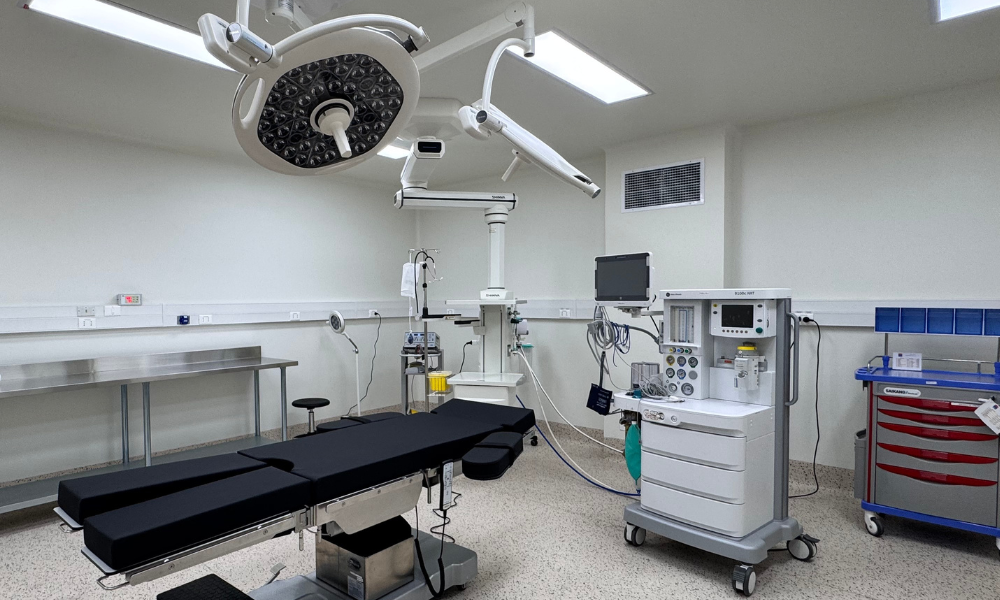 Operating room with a surgical table, overhead lights, and anesthesia/monitoring equipment ready for procedure