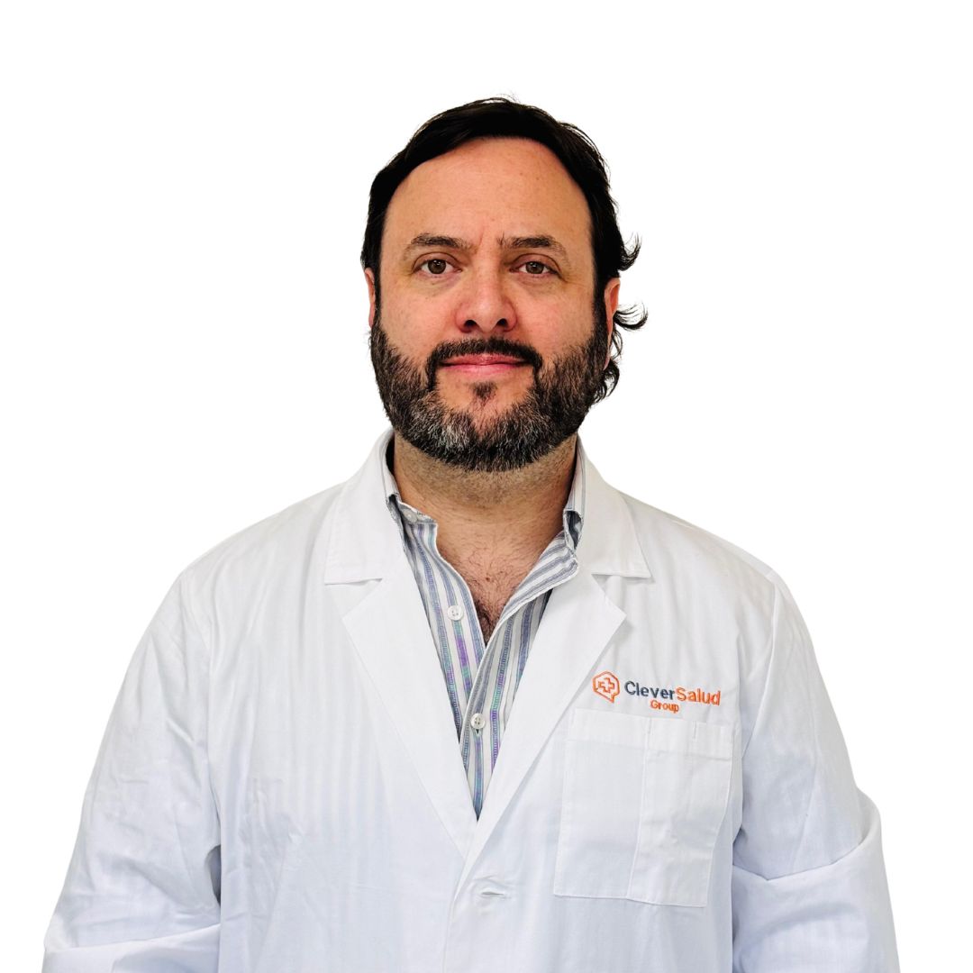 Portrait of a male doctor in a white lab coat with the Clever Salud Group logo on the chest pocket, facing the camera.