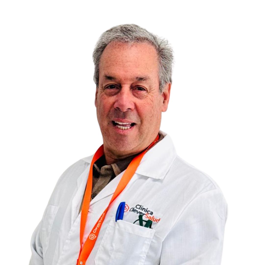 Older male doctor in a white lab coat with an orange lanyard, smiling at the camera.