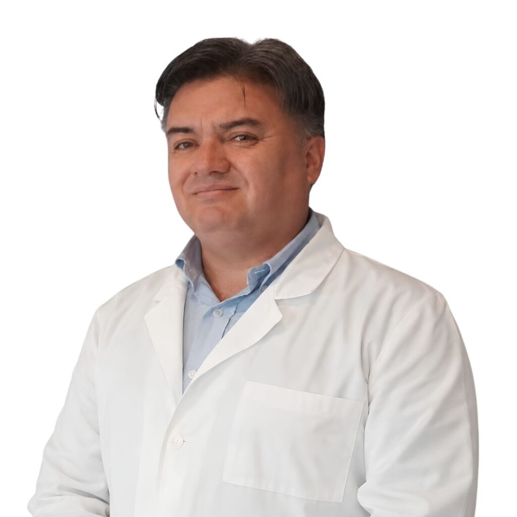 Smiling male doctor in a white lab coat against a white background.