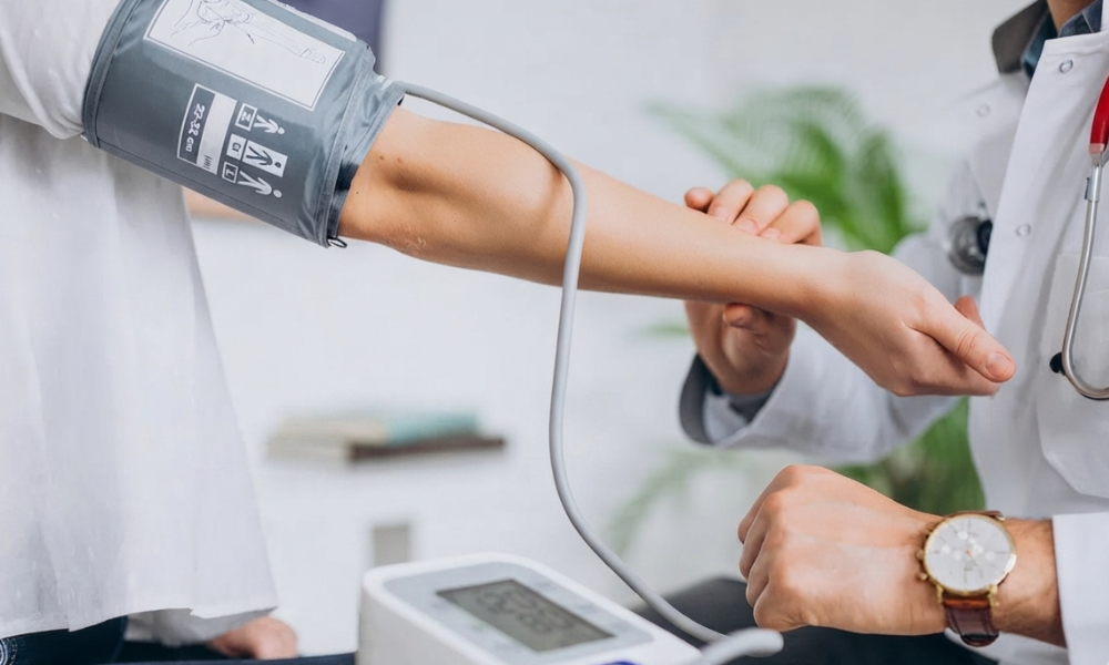 Healthcare professional takes a patient’s blood pressure using a cuff on the upper arm.