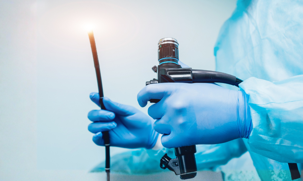 Clinician in blue gloves holds a flexible endoscope with a light at the tip, ready for a procedure.