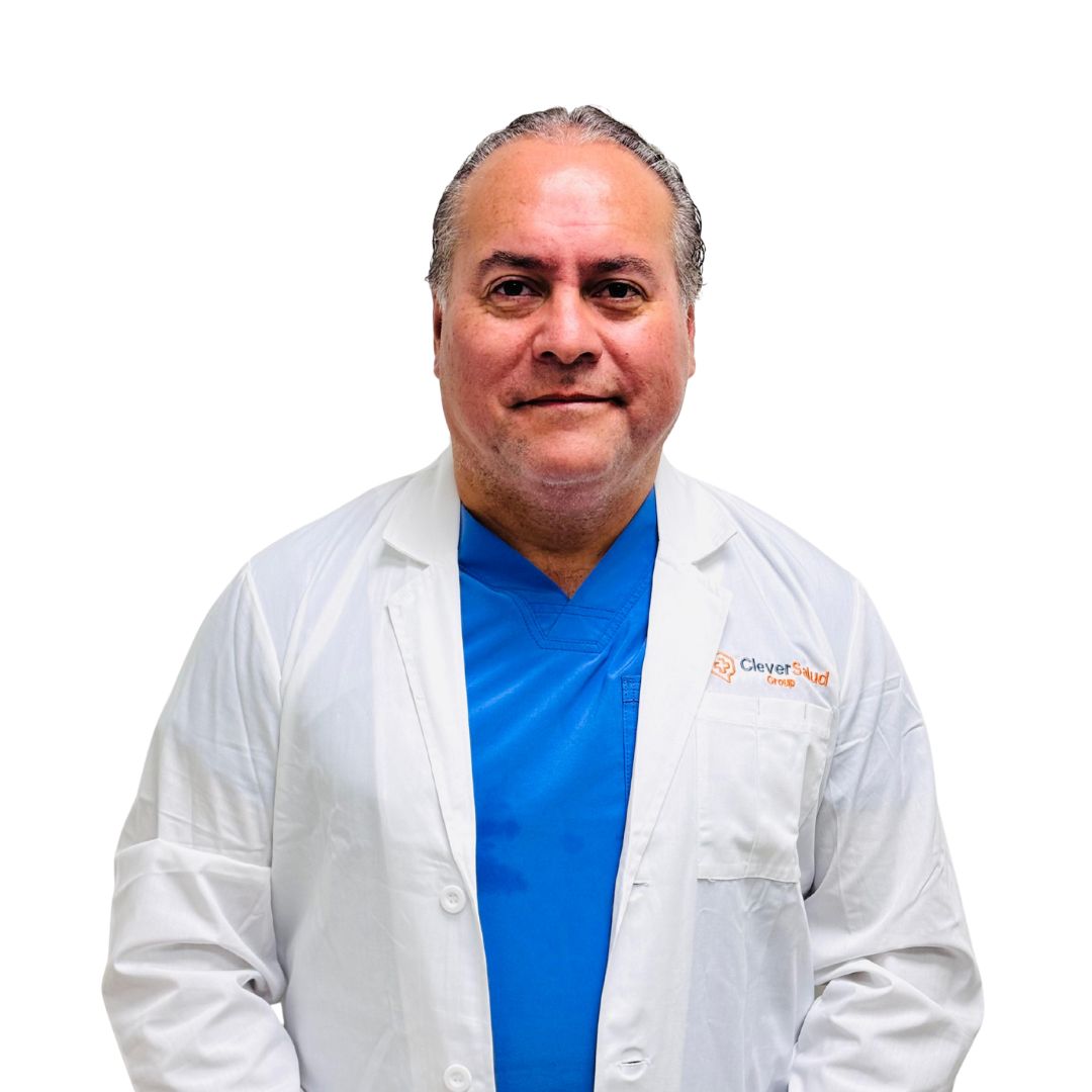 Smiling male doctor in a white lab coat over blue scrubs, posing against a white background.