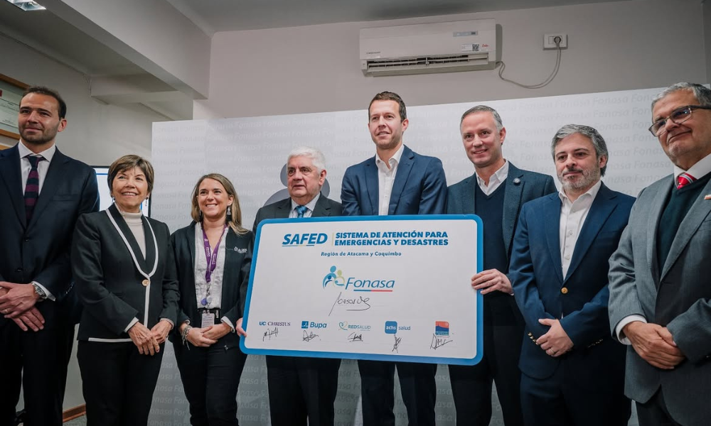 Eight professionals in business attire pose indoors, holding a blue-bordered sign featuring the SAFED logo and text about emergency and disaster response.
