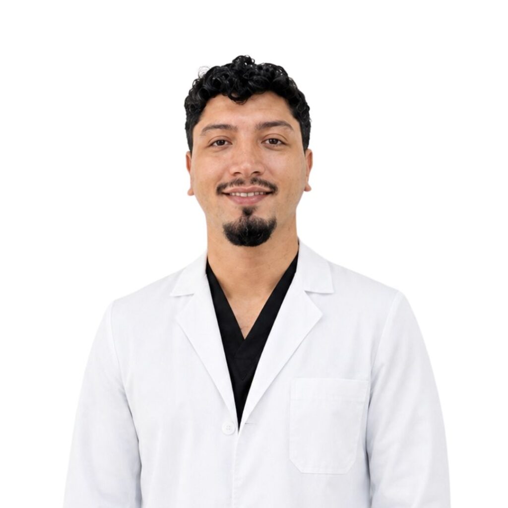 Smiling man in a white lab coat with a black shirt underneath, posed against a white background, professional portrait.